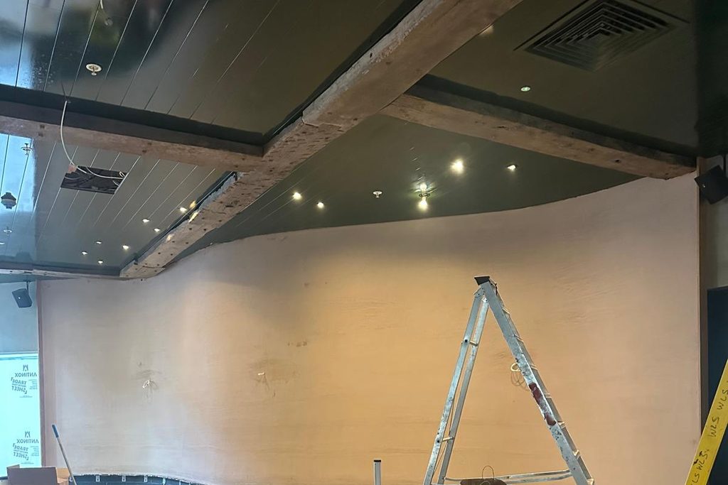 A curved feature wall meeting a coffered ceiling, plastered to a continuous radius. Photographed during finishing.